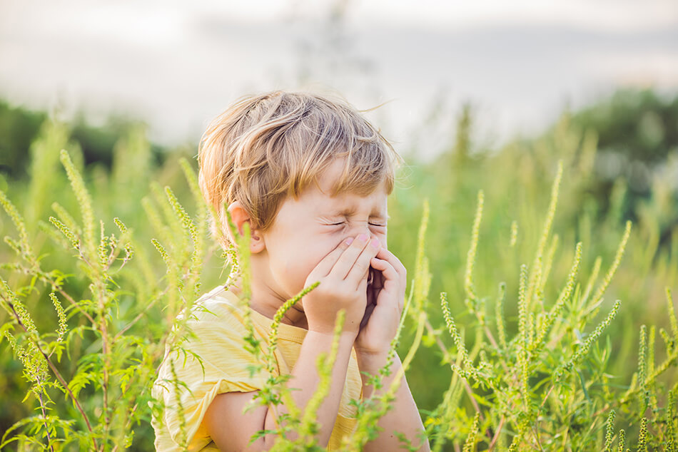 boy is outdoors bothered by seasonal allergies