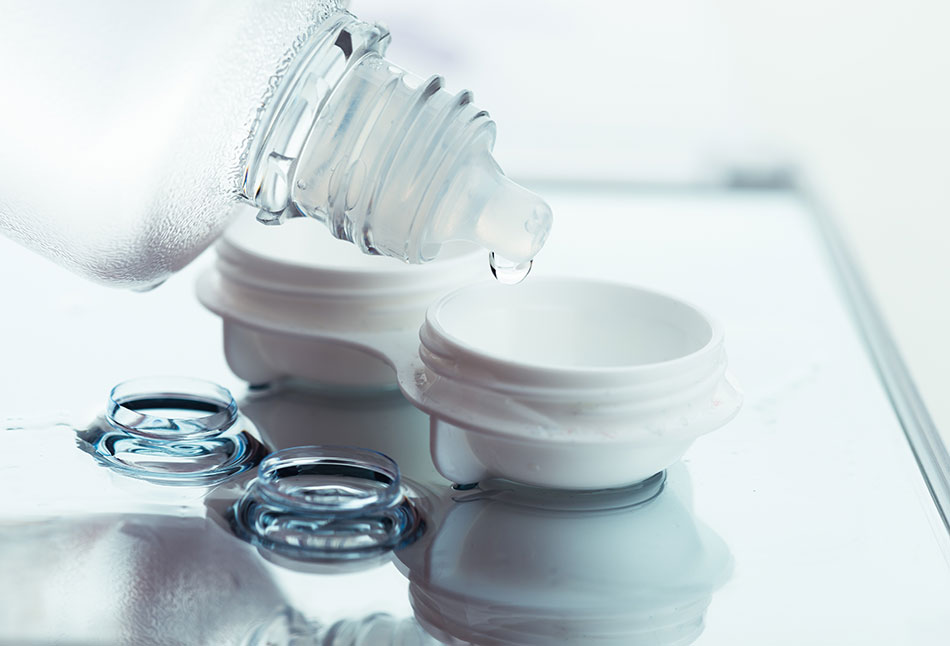 contact lens solution being put into a contact case with lenses on a table