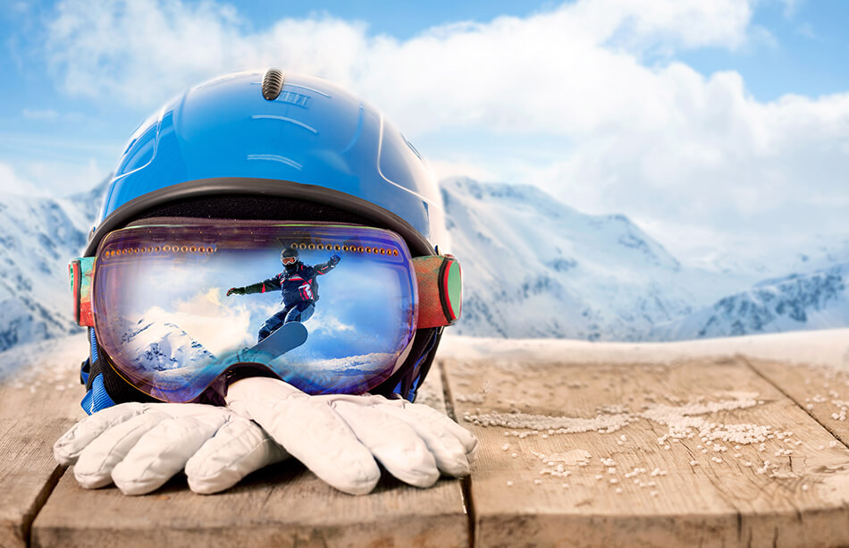 sports goggles, helmet and winter gloves with mountains in background