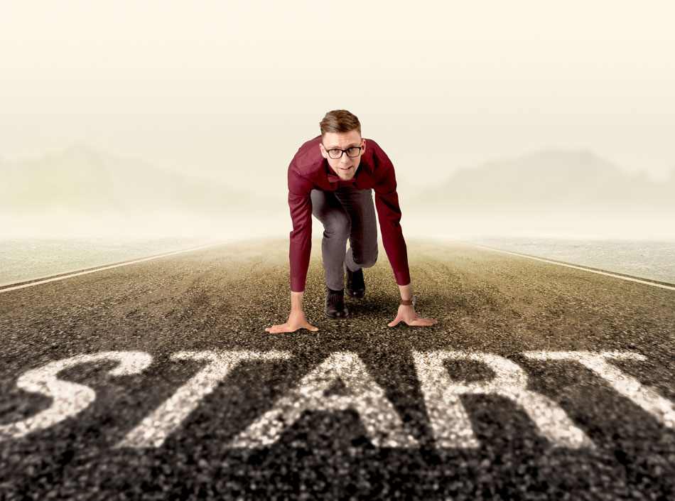 man with glasses crouching at the running start line