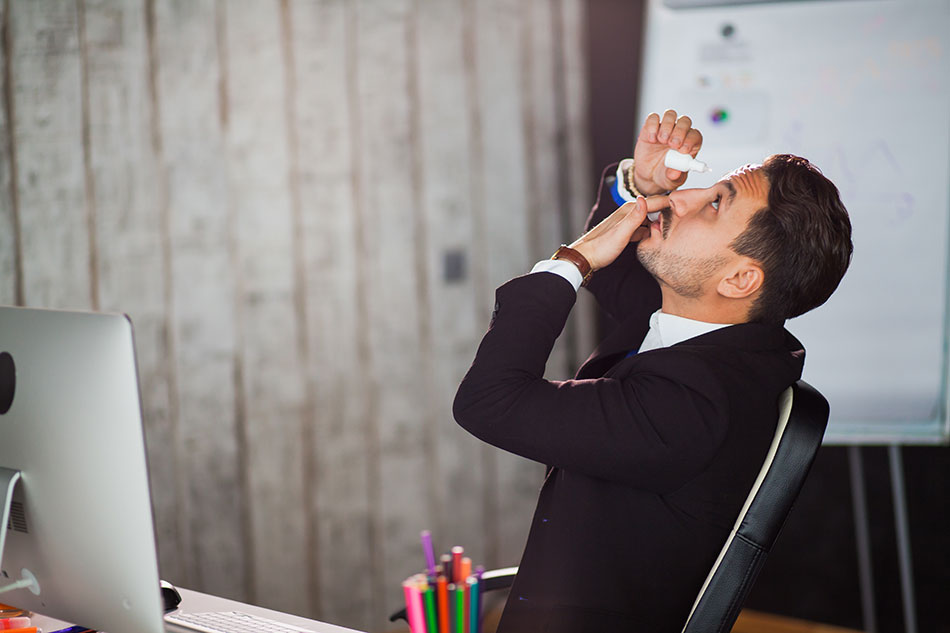 Man in office using prescription eye drops