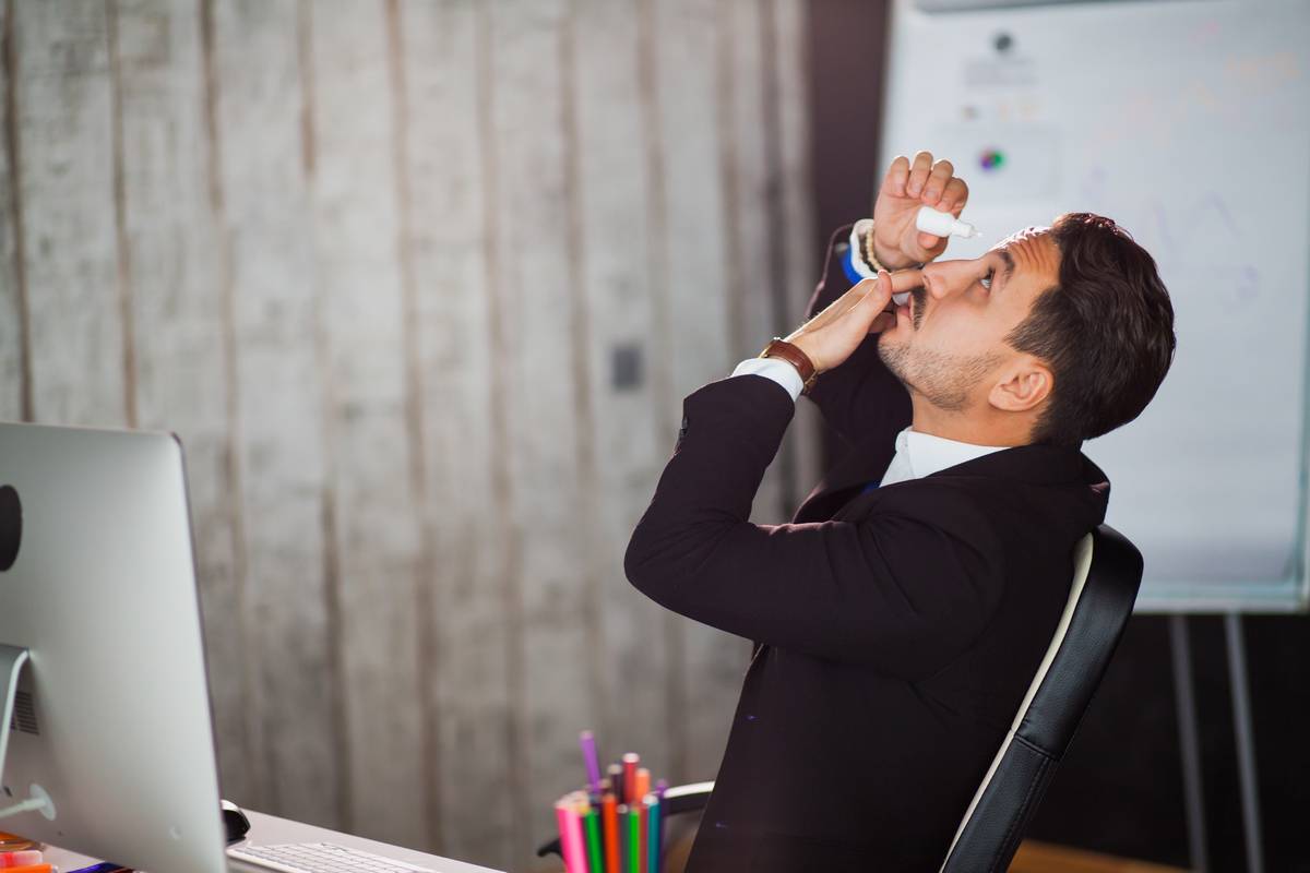 man in office using eye drops