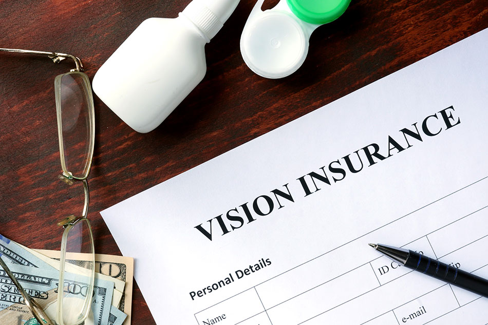 vision care insurance form on desk with pen, eyeglasses, money and contact lenses storage case.