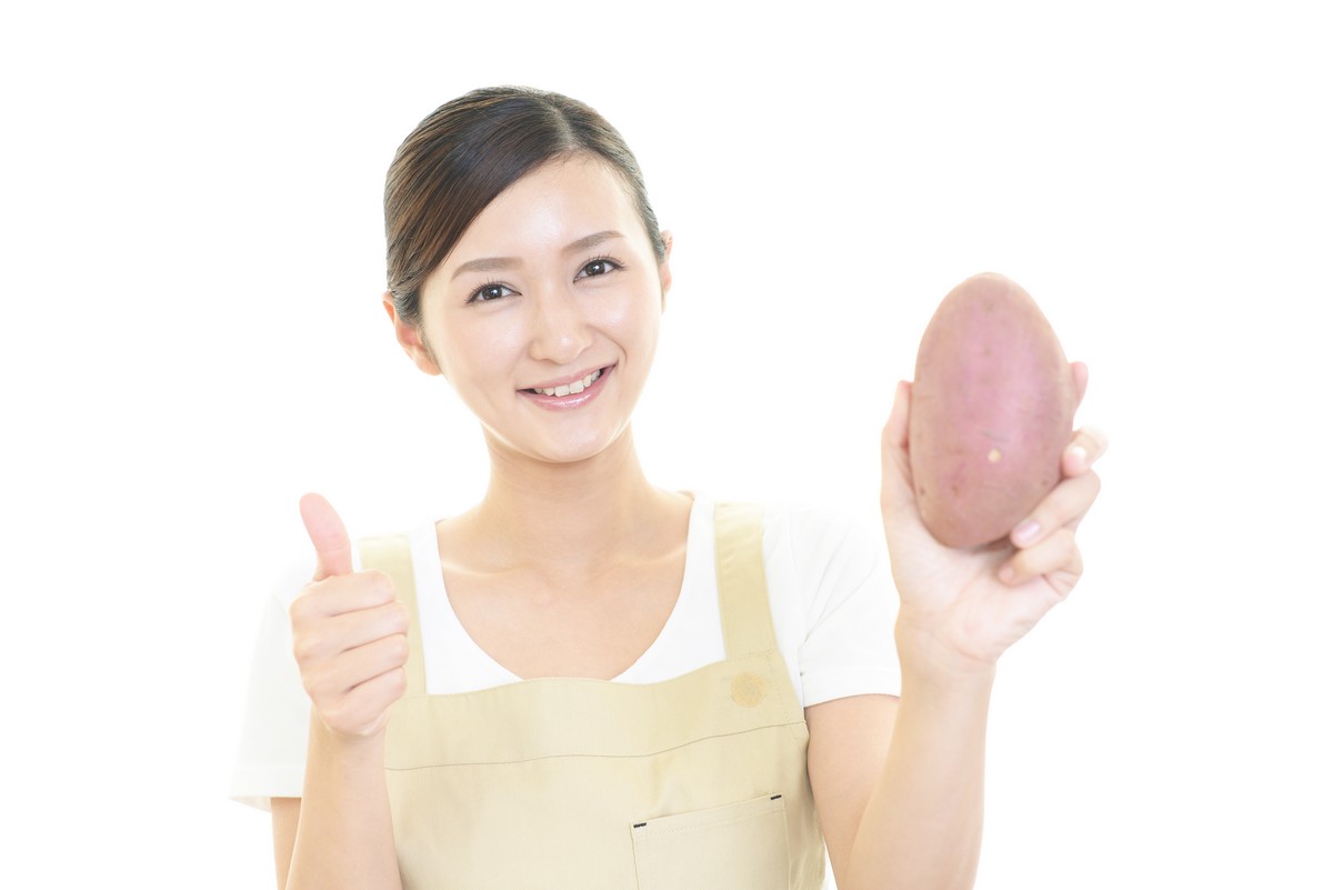 woman holding a sweet potato and giving thumbs up sign
