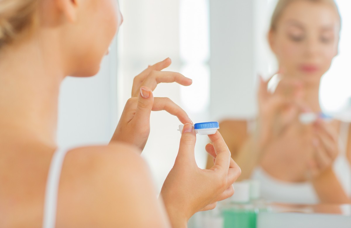 woman putting contact lens into case