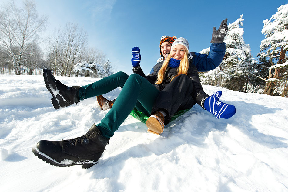 young couple sledding in snow