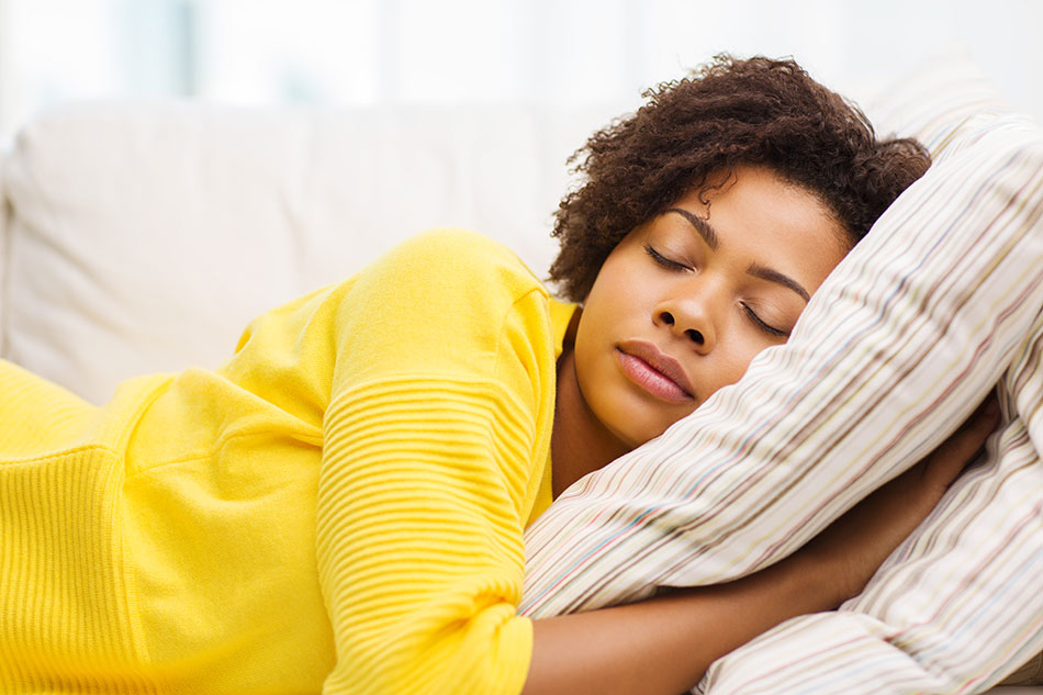 young woman in yellow sweater asleep on sofa